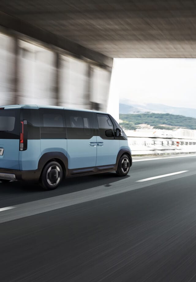 Rückansicht des Kia PV5 Passenger, der auf der Autobahn fährt – mit einem weiteren Kleinbus voraus.